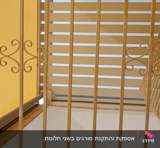 סורגים ישרים ממתכת בצבע קרם עם עיטורים דקורטיביים בחלון